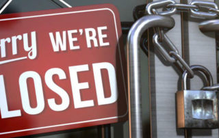 Locked doors with closed sign to indicate business shutdown